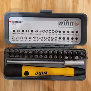Könnte beinhalten: Geöffnete graue GoBox mit einer Auswahl an Wiha Schraubendreherbits und einem gelb-schwarzen Schraubendrehergriff. Die Box zeigt das Wiha-Logo und den Text "Tools that work for you".