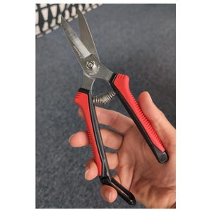 Puede incluir: Tijeras de jardinería con cuchillas de acero inoxidable y mangos rojos y negros. Las tijeras tienen un mecanismo de resorte y un lazo de bloqueo. El texto "MADE IN KOREA" es visible.