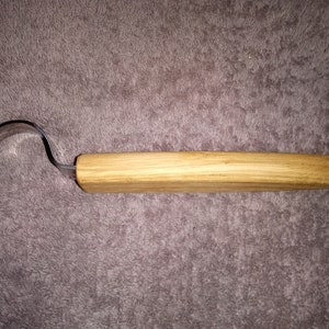 May include: A wood carving tool with a curved metal blade and a wooden handle.