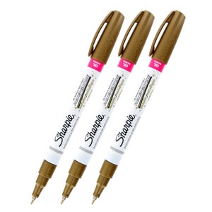 Könnte beinhalten: Drei goldene Sharpie Öl-basierte Malmarker mit dem Text "Metallic/Métallique" und "Oil Based" auf der Seite der Marker.