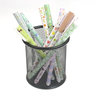 K&ouml;nnte beinhalten: Ein schwarzer Draht-Bleistiftbeh&auml;lter gef&uuml;llt mit bunten Stiften mit verschiedenen Mustern. Die Stifte haben gr&uuml;ne, rosa und wei&szlig;e Designs mit dem Text "Happy Every Day".
