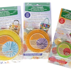 May include: Three Clover brand Quick Yo-Yo Makers in different sizes. The makers are yellow, orange, and green. Each maker has a circle with a hole in the center and a ring around the outside. The packaging includes instructions for making yo-yos.