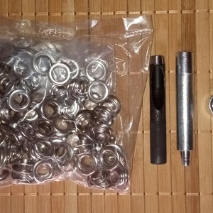 May include: A set of silver eyelets in a clear plastic bag, a black eyelet tool, and a silver eyelet tool.