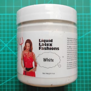 May include: A white jar of Liquid Latex Fashions. The label features a woman in a red outfit holding a trident. The word "White" is in a speech bubble. Net weight is 4 oz.