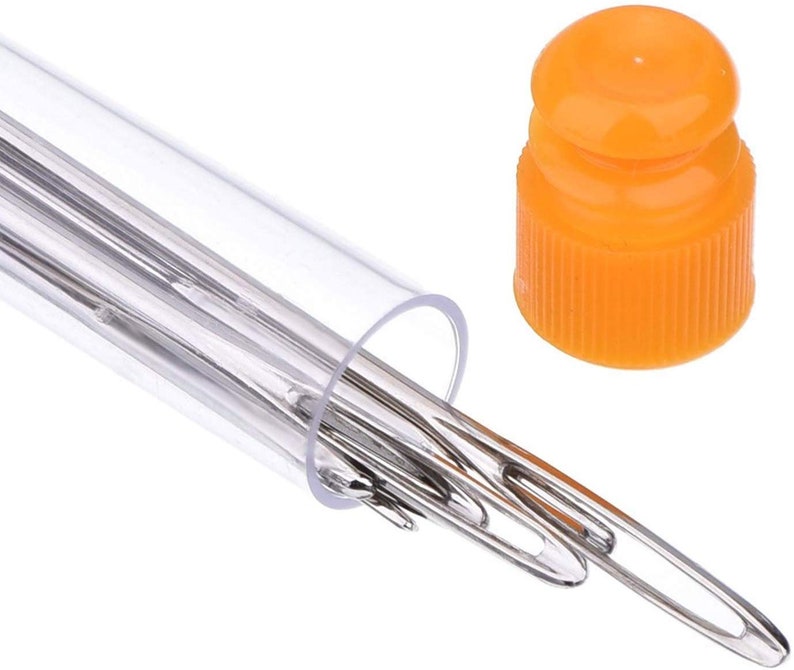 Op de afbeelding: Een transparante plastic buis met een set zilveren naalden. De buis heeft een oranje plastic dop.