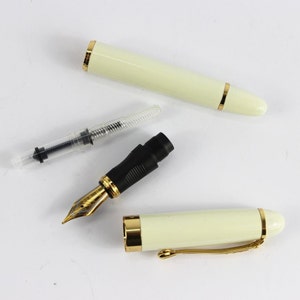 May include: A white fountain pen with gold accents and a black nib. The pen is disassembled, showing the nib, the converter, and the pen body.