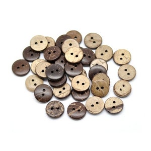 May include: A pile of brown and beige coconut shell buttons. The buttons have two holes each and are arranged in a random pattern.