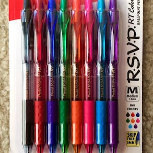May include: A package of eight Pentel RSVP RT ballpoint pens in assorted colors. The pens have clear barrels and colored ink, with a medium 1.0mm tip. The package is red and white, with the Pentel and RSVP RT logos visible.