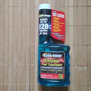 以下が含まれることがあります： スター・トロン・エンザイム・フューエル・トリートメントの青いボトル。ボトルには、「スター・トロン・エンザイム・フューエル・トリートメント」と「スタビライズ・アップ・トゥ・2・イヤーズ」の文字が書かれています。ボトルには、「トリート・アップ・トゥ・128・ガロン」の文字も書かれています。