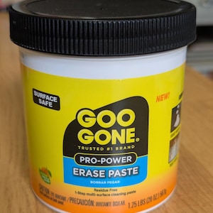 Puede incluir: Un envase cilíndrico amarillo de Goo Gone Pro-Power Erase Paste con tapa negra. La etiqueta incluye el nombre de la marca y detalles del producto, indicando que no deja residuos y es seguro para superficies. El envase pesa 567 gramos.