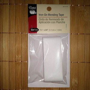 May include: A white iron-on mending tape in a clear plastic package. The package is labeled "Iron-On Mending Tape" and "Cinta de Remiendo de Aplicación con Plancha". The size is 1 1/4" x 64" (3.1cm x 1.6m).