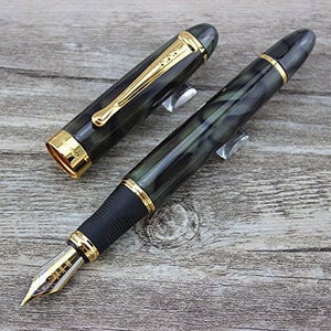 May include: A black and green fountain pen with gold accents and a black cap. The pen has a marbled design and a gold nib.
