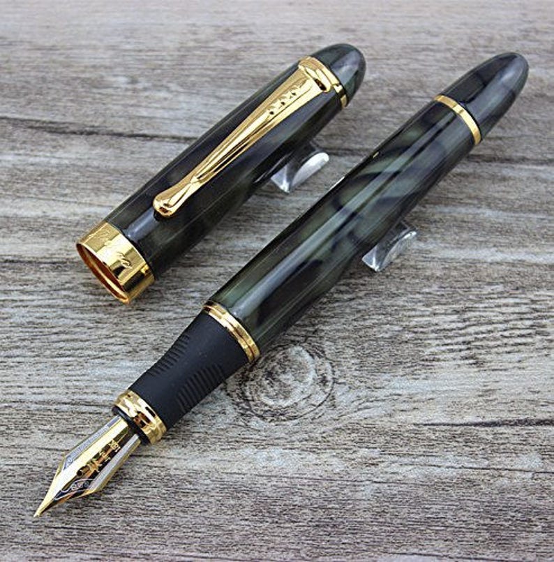 May include: A black and green fountain pen with gold accents and a black cap. The pen has a marbled design and a gold nib.