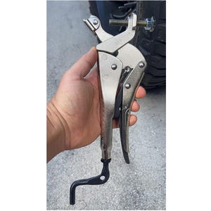May include: A silver locking pliers tool with a black handle and a curved black hook at the end. The tool has a bolt and nut adjustment mechanism. The pliers are held in a hand.