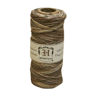 May include: A spool of brown and beige hemp twine with a label that reads "Hemptique 100% Hemp Cord 205 feet hemptique.net".