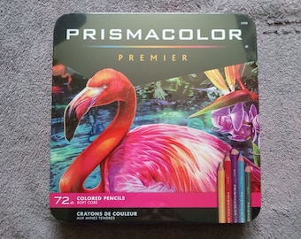 Könnte beinhalten: Eine Schachtel mit 72 Prismacolor Premier Farbstiften mit weicher Mine. Die Schachtel zeigt ein farbenfrohes Bild eines rosa Flamingos in einer tropischen Umgebung. Der Text "Crayons de Couleur aux Mines Tendres" ist auf der Schachtel aufgedruckt.