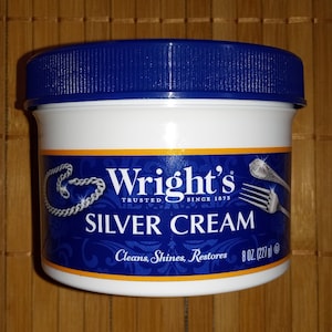Pode incluir: Um frasco azul e branco de creme para prata Wright's. O frasco tem uma tampa azul e um rótulo que diz "Wright's Trusted Since 1873 Silver Cream Cleans, Shines, Restores 8 oz (227 g)".