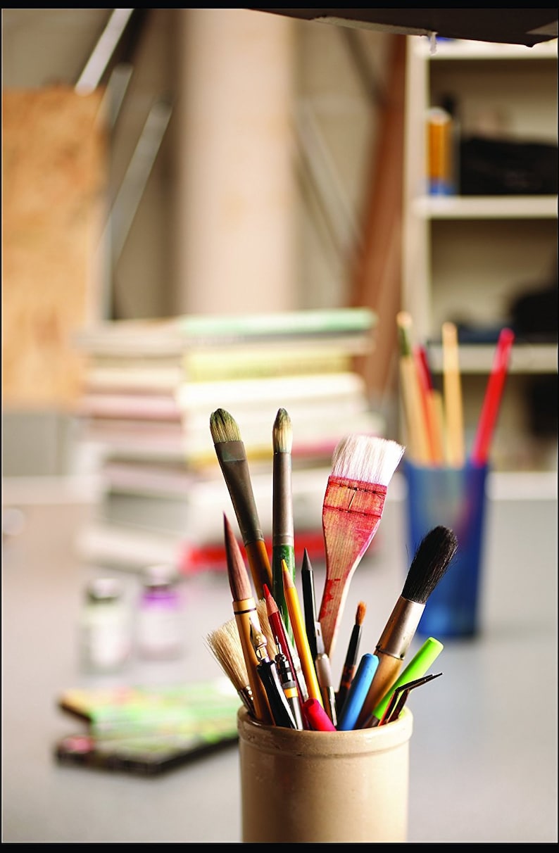 May include: A close-up of a ceramic jar filled with a variety of paintbrushes, including round, flat, and angled brushes. The brushes are in various sizes and colors, including black, brown, red, and green.