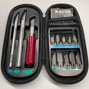 以下が含まれることがあります： ジッパー付きの黒いキャリングケースには、X-ACTO精密機器のセットが入っています。ケースには、ブレードが見える透明なプラスチック製の窓が付いています。ケースには、X-ACTOのロゴと「Precision Instruments Guide Book」という文字が書かれた小さなガイドブックも含まれています。