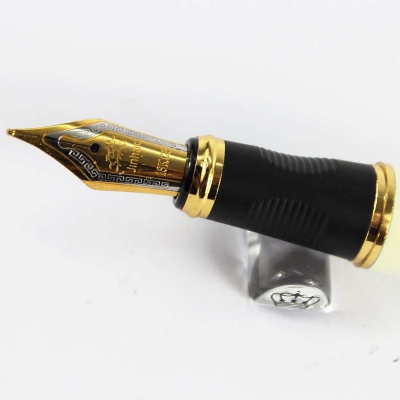 May include: A gold and black fountain pen with a black and white nib. The nib is engraved with the text "Jinhao 159".