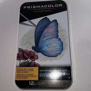 Może przedstawiać: Zestaw do rysowania zwierząt Prismacolor Technique w metalowym pudełku. Pudełko zawiera szczegółową ilustrację niebieskiego motyla z czerwonymi kwiatami. Zestaw zawiera 12 kolorowych ołówków i instrukcje krok po kroku.