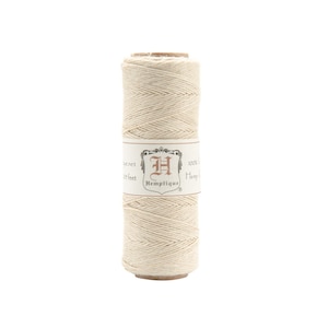 Puede incluir: Una bobina de cuerda de cáñamo de color natural, 100% cáñamo, con una etiqueta que dice "Hemptique 100% Hemp Twine 25 feet".