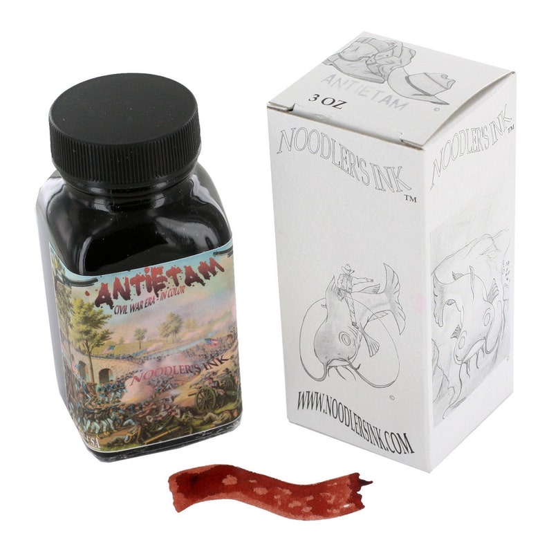 May include: A 3 oz bottle of Noodler's Ink Antietam ink. The bottle is black with a label depicting a Civil War era battle scene. The ink is a dark brown color. The bottle is sitting on a white background. The ink is packaged in a white box with a black and white illustration of a man riding a fish.