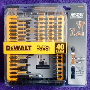 Puede incluir: Un juego de 40 puntas de destornillador DeWalt Impact Ready con tecnología FlexTorq, de color amarillo y negro. El juego incluye una variedad de tamaños y tipos de puntas, incluyendo Phillips, planas y Torx. Las puntas están empaquetadas en un estuche de plástico transparente con una etiqueta amarilla y negra.