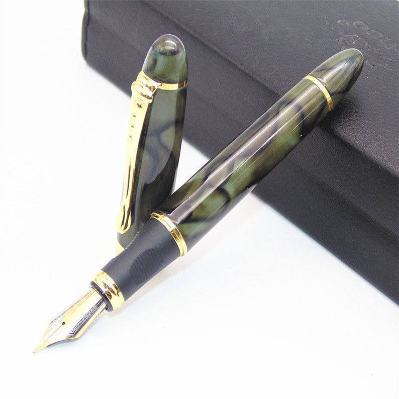May include: A green and black fountain pen with gold accents. The pen has a marbled design and a black cap.
