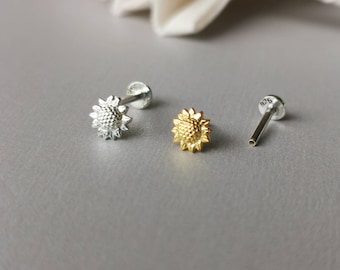 以下が含まれることがあります： 銀製のひまわりスタッドピアス3つ。2つのピアスはひまわりのデザインで、もう1つのピアスはシンプルなポストです。