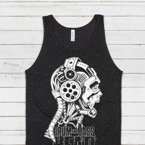 May include: A charcoal gray sleeveless tank top featuring a white graphic print of a mechanical human head profile wearing headphones with intricate gears and wires, accompanied by the bold white text reading DRUM AND BASS HEAD.