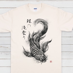 May include: A white t-shirt featuring a black and white illustration of a koi fish and Japanese calligraphy that reads "真意 受け" on the front.