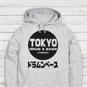 May include: A gray hoodie with a black circle graphic that says "Tokyo Drum & Bass" in white text. The Japanese text "ドラムベース" is below the circle.