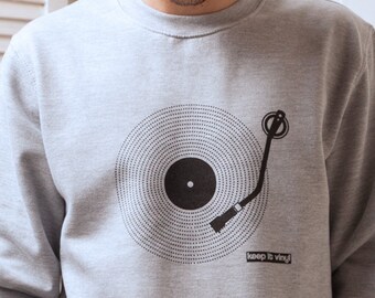 May include: A gray sweatshirt with a black graphic of a record player and the text "keep it vinyl". The model is wearing a gray and black baseball cap.