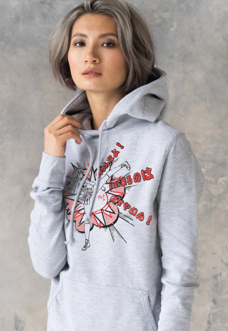 Puede incluir: Sudadera gris con capucha con un estampado gr&aacute;fico de una chica pateando un objetivo con el texto "&iexcl;No te metas con mis amigos!" en japon&eacute;s e ingl&eacute;s.
