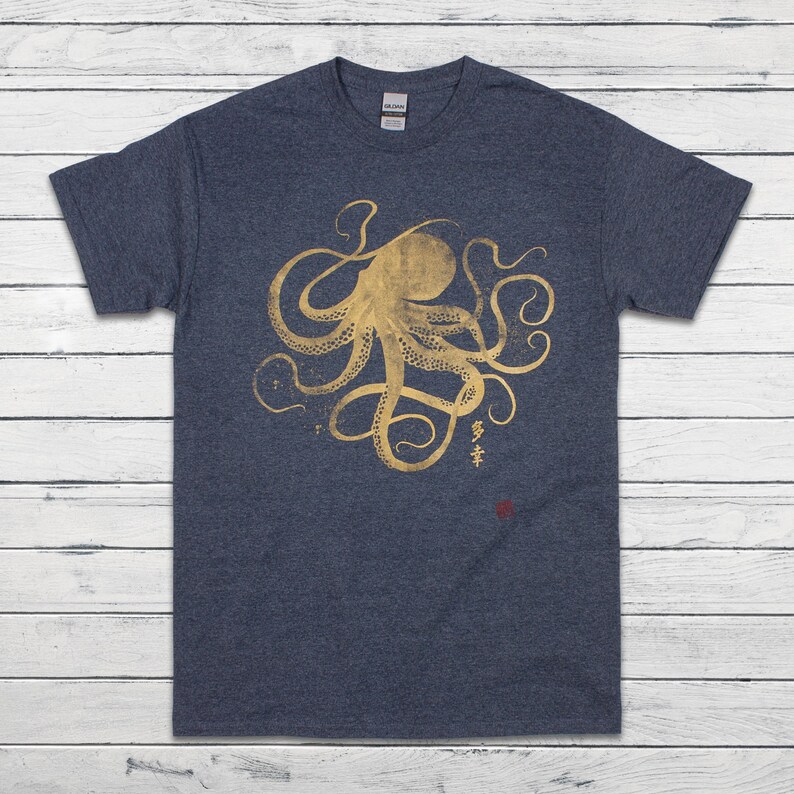 Pode incluir: Camiseta azul marinho com um desenho de polvo dourado. A ilustra&ccedil;&atilde;o do polvo inclui caracteres japoneses e um selo vermelho. A camisa &eacute; feita de um material macio.