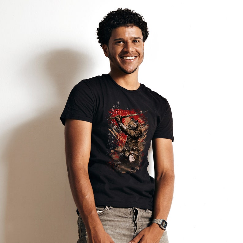 May include: A black t-shirt with a graphic print of a samurai warrior holding a sword. The warrior is depicted in a stylized, abstract style with splashes of red and brown paint.
