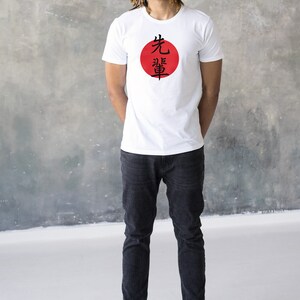 May include: A white t-shirt with a red circle and black Japanese characters that say "先導" on it.