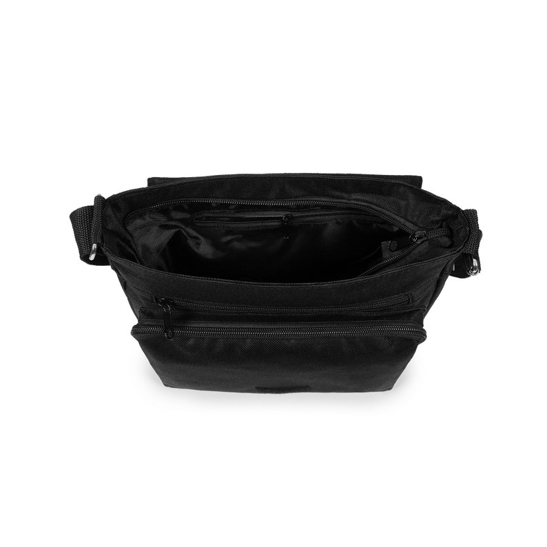 May include: A black crossbody bag with a top zipper closure, an open main compartment, and two additional horizontal zippered pockets on the front. The bag features a woven adjustable shoulder strap attached with silver-toned metal hardware.