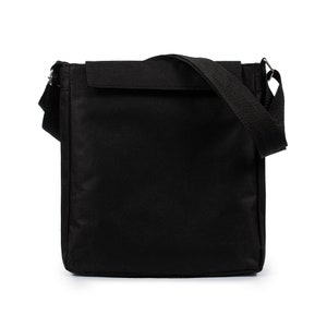 May include: A solid black rectangular messenger bag featuring a fold-over flap closure, a wide adjustable shoulder strap attached with silver-toned metal hardware, and a structured vertical orientation with clean, minimalist stitching throughout.
