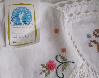 May include: White embroidered tablecloth with a floral design and a lace border. The tablecloth has a tag that says "Clever Fingers" and "Made in China".
