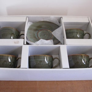 May include: A set of six green teacups and saucers in a white box. The cups and saucers have a mottled green glaze.