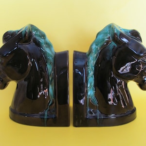 May include: A pair of black and turquoise ceramic horse head bookends. The horse heads are facing opposite directions and have a glossy finish.