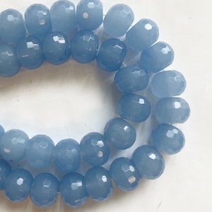 K&ouml;nnte beinhalten: Eine Str&auml;hne aus hellblauen facettierten Glasperlen. Die Perlen sind rund und haben eine glatte, polierte Oberfl&auml;che.