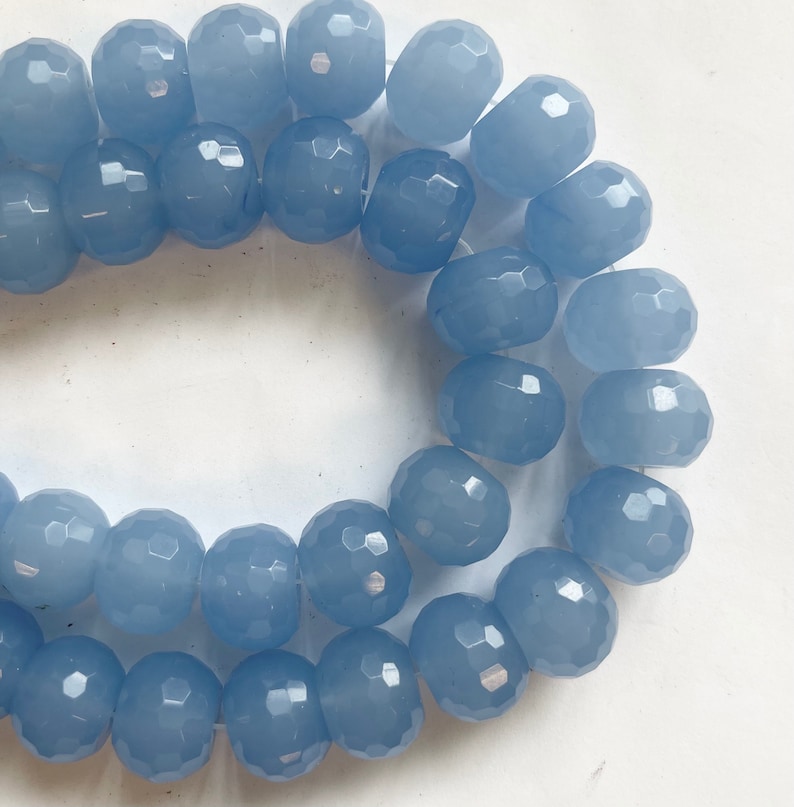 K&ouml;nnte beinhalten: Eine Str&auml;hne aus hellblauen facettierten Glasperlen. Die Perlen sind rund und haben eine glatte, polierte Oberfl&auml;che.