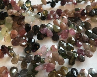 May include: A strand of faceted, teardrop-shaped, multi-colored tourmaline beads. The beads are a mix of green, pink, and black.