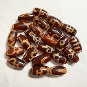 May include: A collection of 20 brown and white agate beads with intricate patterns. The beads are oval shaped and have a smooth, polished finish.