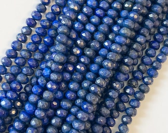 Pode incluir: Um fio de contas de lapis-lazúli facetadas azul-escuro. As contas são redondas e têm um acabamento liso e polido.
