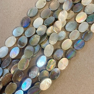 May include: Strands of iridescent oval-shaped beads in shades of gray, white, and hints of blue and green. The beads have a pearlescent sheen, reflecting light. These beads are suitable for jewelry making.