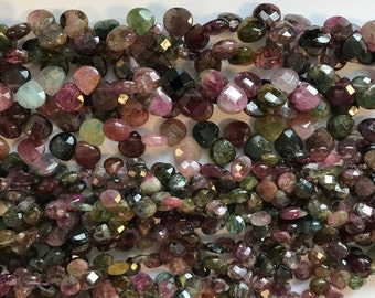 May include: A strand of faceted, heart-shaped, green, pink, and black tourmaline beads. The beads are approximately 8mm in size and have a natural, polished finish.